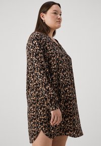 Μαύρο φόρεμα με λουλουδένιο μοτίβο σε αποχρώσεις μπεζ; διαθέτει μακριά μανίκια, V-λαιμόκοψη και πλαϊνές σχισμές για επιπλέον κίνηση.