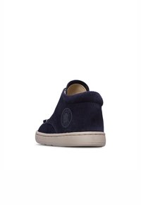 Stivaletto in suede blu navy con punta rotonda, lato elastico e suola in gomma crema. Presenta un logo circolare impresso sul lato esterno.