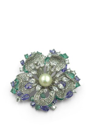 Spilla floreale in argento con una perla centrale, adornata con pietre preziose trasparenti, verdi e viola disposte a forma di petali e accenti circostanti.