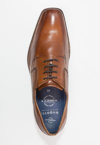 Chaussure habillée en cuir marron avec une finition lisse, bout arrondi, et lacets noirs. Présente des accents perforés sur les côtés et une semelle intérieure bleu marquée "Comfort Fit".