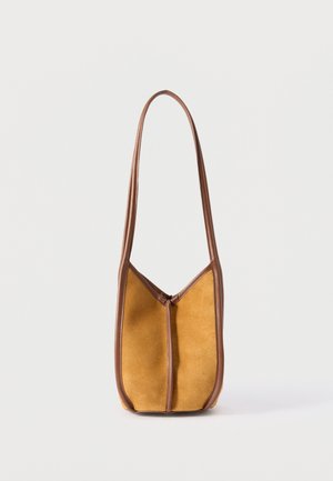 Small brown suede shoulder bag with long leather strap and leather trim, standing upright on a plain white background.