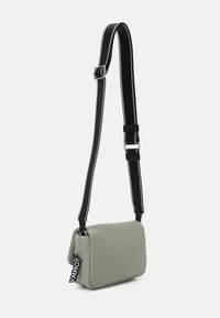 Borsa a spalla verde, con una texture morbida e un design a pattina, cinturino regolabile nero con cucitura bianca e un'etichetta "YMMOT" removibile.