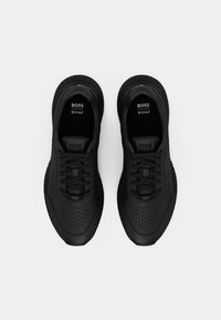 Zapatillas negras con parte superior de cuero suave, detalles perforados, cordones negros y cuello acolchado. Presenta el logotipo de la marca en la lengüeta y la plantilla.