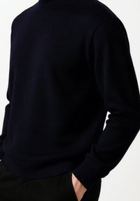 Námořnický svetr s žebrovaným kulatým výstřihem, dlouhými rukávy a přiléhavým střihem, vyrobený z měkkého, strukturovaného pleteného materiálu.