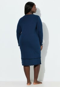 Camisa de noche azul marino de manga larga, tela suave, dobladillo con borde festoneado y un detalle decorativo de punto cerca del borde inferior. Cuenta con un escote redondo.