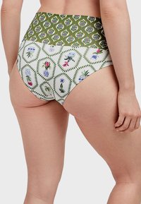 Parte inferior de bikini de tiro alto con una cinturilla de estampado floral verde y cuerpo blanco que presenta patrones florales multicolores. Textura de tela suave.