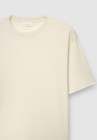 Cremefarbenes, geripptes T-Shirt mit rundem Halsausschnitt und kurzen Ärmeln. Der Stoff hat ein strukturiertes Muster und ein Etikett mit der Aufschrift "Callipe Man L."