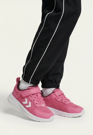 Child wearing black pants and white socks with pink athletic shoes featuring velcro straps and white sole standing on a white background.