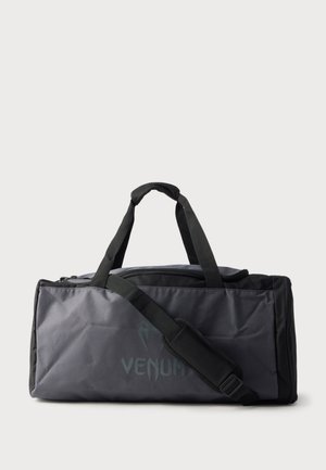 Sac de sport Venum noir et gris avec doubles poignées et bandoulière réglable sur fond blanc uni.