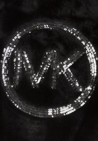 Písmena MK ve stříbrných flitrech tvořící kruh na černém texturovaném látkovém pozadí.