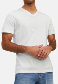 Hvid v-hals t-shirt lavet af bomuld, med korte ærmer og en afslappet pasform, parret med blå denim jeans. Enkel, udekoreret design.