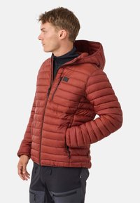 Rode pufferjack met horizontale gestikte textuur, vaste capuchon, ritssluiting aan de voorkant en zijzakken, gedragen over een zwarte top.