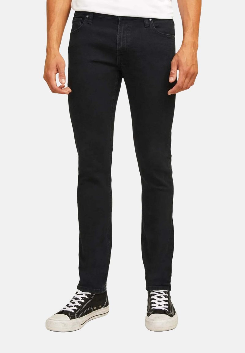 Jeans in denim nero con vestibilità slim, dotati di un classico design a cinque tasche e zip, abbinati a sneaker alte nere.