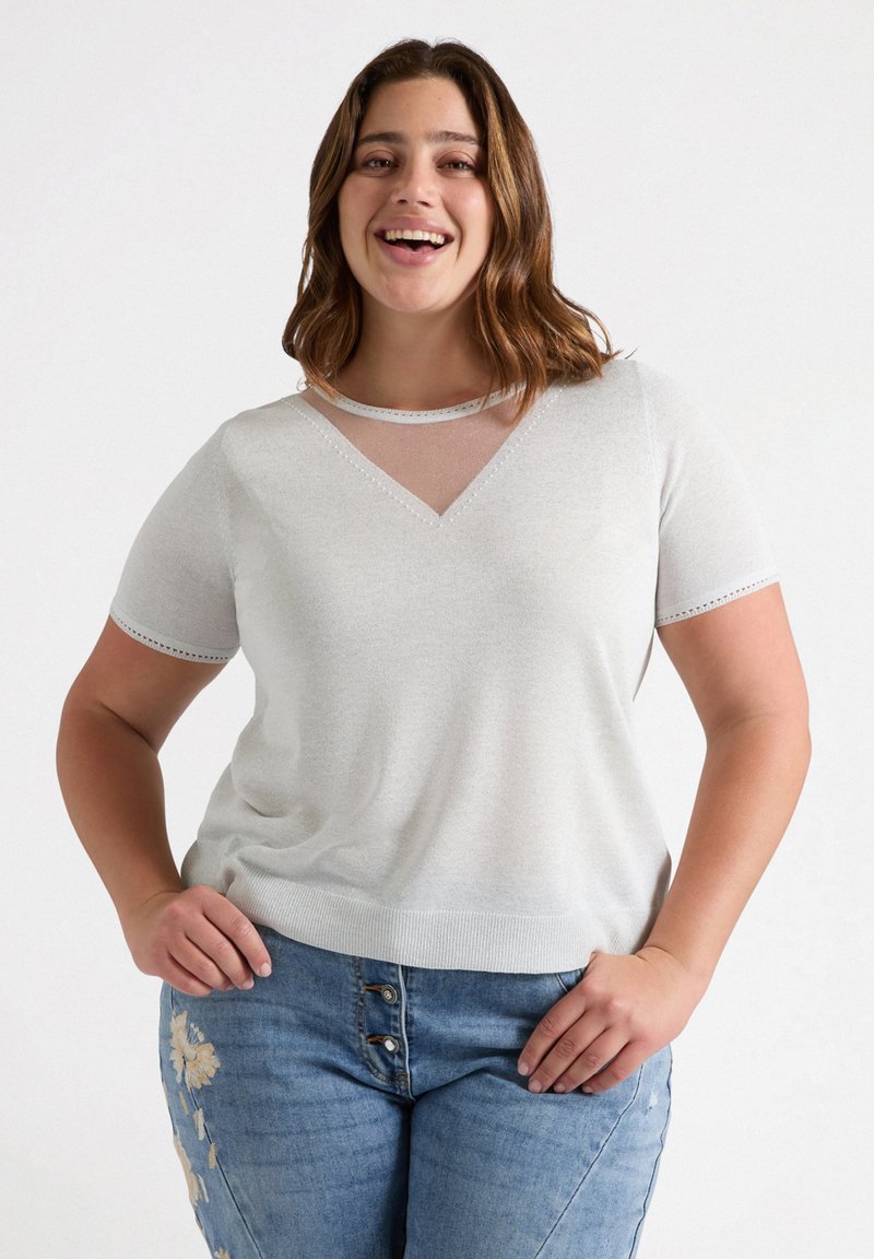 Jasnoszary, krótki top z rękawami, z dekoltem w serek i przezroczystą wstawką przy dekolcie. Posiada dekoracyjne przeszycia wzdłuż brzegów oraz miękką fakturę.