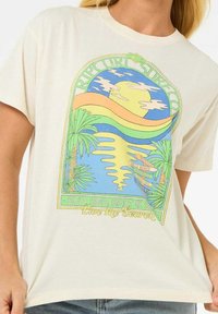 Camiseta de algodón color crema con un gráfico colorido inspirado en la playa que incluye palmeras, sol y texto en negrita. Mangas cortas, corte relajado.