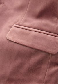 Różowa marynarka z gładkiego materiału, z pojedynczą kieszenią z przodu i subtelnymi detalami szwów.