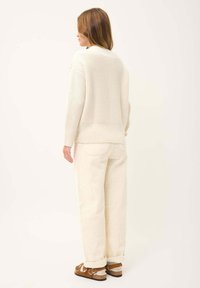 Cremfarbener Strickpullover mit lockerer Passform, kombiniert mit cremf claimt Sweetcordhosen. Das Outfit zeichnet sich durch ein strukturiertes Muster und legere Schuhe aus.