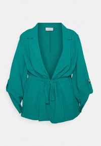 Blus i blågrönt med V-ringning, lösa ärmar och knytband i midjan. Tillverkad av lätt tyg med en mjuk textur och krage.