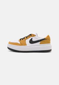 Tenisky Nike s bílým svrškem, žlutými semišovými akcenty, černým logem swoosh a silnou bílou podrážkou s černou gumovou podešví.