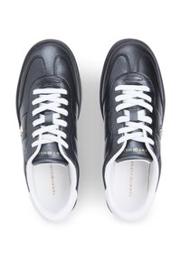 Μαύρα δερμάτινα αθλητικά παπούτσια με λευκά κορδόνια και λαστιχένιες σόλες. Διαθέτουν χρυσά διακοσμητικά λογότυπα. Στρογγυλεμένη μύτη και επενδεδυμένα πέλματα για άνεση.