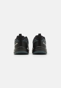 Zapatillas deportivas negras con parte superior de malla texturizada, talón reforzado y suela de goma, con acentos azules y tiradores en la parte posterior.