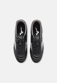 Svarta skor i slät läderfinish, med grå accenter och en strukturerad sula. Utrustade med snören och logotyp på tungan.