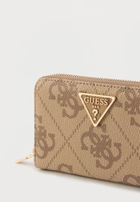 Portofel maro cu fermoar pe margine, cu model embosat, logo triunghiular auriu și material texturat. Dispune de un element de prindere pentru fermoar la închidere.