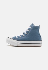 Kanga-Nike korko-kangas kengät tummansinisessä denim-värissä, joissa on valkoiset nauhat, mustat reunukset ja teksturoitu kumipohja, jossa on kontrastoiva ruskea pohja.