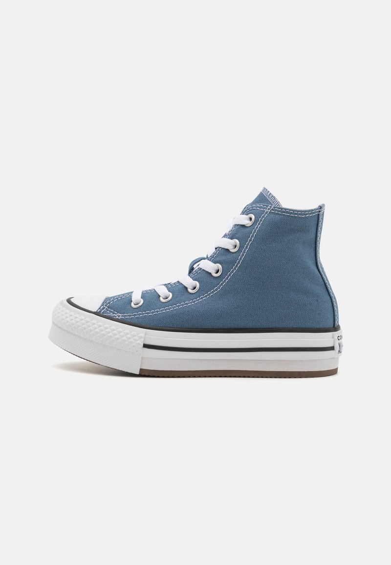 Kanga-Nike korko-kangas kengät tummansinisessä denim-värissä, joissa on valkoiset nauhat, mustat reunukset ja teksturoitu kumipohja, jossa on kontrastoiva ruskea pohja.