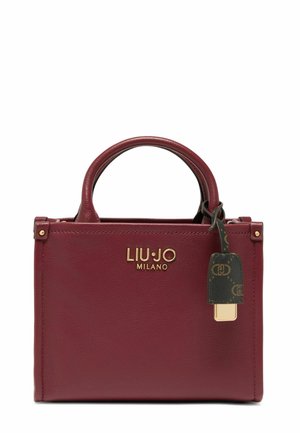 Burgundy leather handbag with gold logo, two rounded top handles, and a decorative tag featuring a patterned design and gold accent.