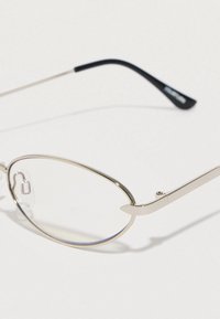 Ochelari de metal cu formă ovală, având rame subțiri de argint și lentile clare, completate cu brațe elegante din plastic negru.
