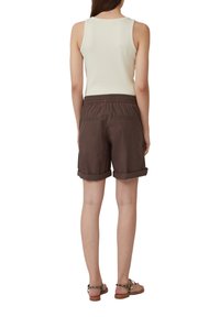 Bruine shorts met omgeslagen manchetten, een elastische tailleband en zijzakken, gecombineerd met een licht tanktop. Sandalen met luipaardprintaccenten.
