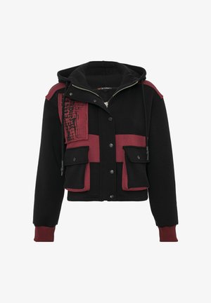 Afgekorte jas met zwart en bordeauxrood stof, knoopsluiting aan de voorkant, dubbele borstzakken en een getextureerd grafisch detail aan de zijkant.