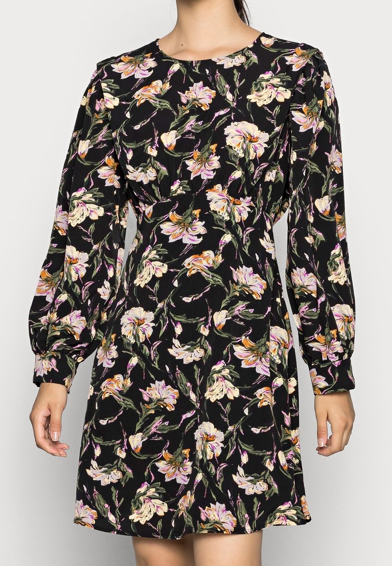 Robe noire à manches longues avec imprimé floral rose et crème, col rond et manches légèrement bouffantes.
