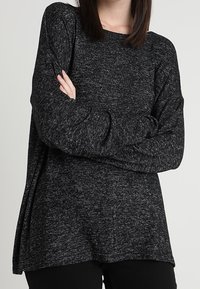 Černý melírovaný svetr s dlouhým rukávem, volným střihem, kulatým výstřihem a spadlými rameny. Texturovaná látka s jemným povrchem.