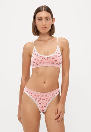Bra and thong set in soft pink fabric with red cherry pattern and white lace accents. The bra has thin straps; the thong has a matching design.