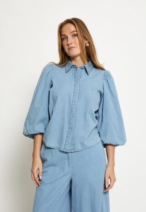 Lichtblauw spijkerblouse met pofmouwen, knoopsluiting en een kraag. Gladde textuur met een relaxte pasvorm en een licht afgeronde zoom.