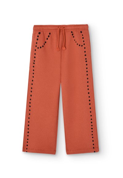 Sweatpants i rustorange farve lavet af blødt stof. Funktioner sorte prikker langs siden og to forlommer med snøre i taljen.