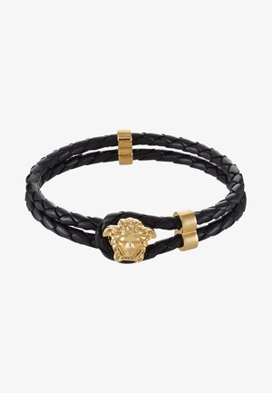 Pulseira de couro trançado preta com fecho em forma de cabeça de medusa dourada e duas peças de destaque em ouro. Design texturizado com acabamentos suaves.