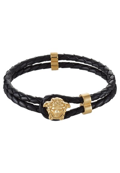 Bracelet en cuir tressé noir avec un fermoir en tête de méduse dorée et deux pièces d'accent dorées. Design texturé avec des finitions lisses.