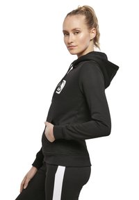 Felpa nera con cappuccio, tasca frontale, cappuccio con cordini e logo ricamato bianco sul petto. Tessuto morbido e design aderente.