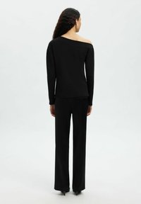 Czarny top bez ramiączek z długimi rękawami, w połączeniu z czarnymi szerokimi spodniami, o gładkiej teksturze i minimalistycznym wzornictwie.