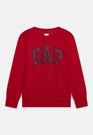 Sweat-shirt rouge à manches longues avec le texte "GAP" en contours bleu marine et "Original" brodé au centre sur un fond uni.