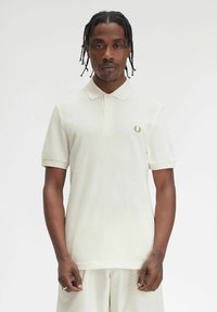 Witte polo-shirt met kraag, korte mouwen en een klein geborduurd logo op de linkerkant van de borst. Gemaakt van gestructureerde stof.