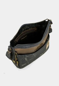 Borsa a spalla nera e marrone con un esterno testurizzato, chiusura a zip e tasche interne. Presenta dettagli scritti e un ciondolo ancorato.