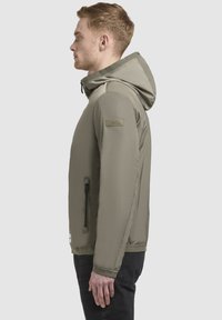 Olivgrüne gepolsterte Jacke mit Kapuze, ausgestattet mit einer seitlichen Reißverschlusstasche und elastischen Bündchen. Glatte Textur und strapazierfähiger Stoff.