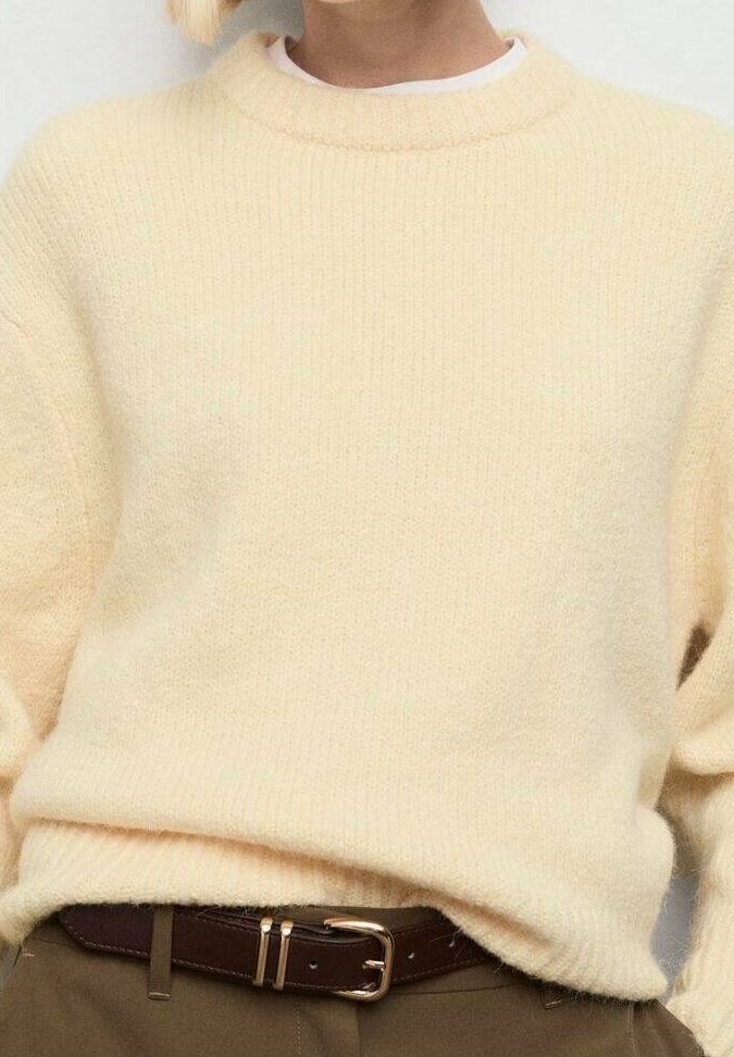 Personne portant un pull tricoté beige clair rentré dans un pantalon marron avec une ceinture marron foncé à boucle dorée.