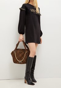 Svart sweatshirtklänning med guld-logga, puffärmar, brun mönstrad handväska med kedja och knähöga svarta stilettklackar.