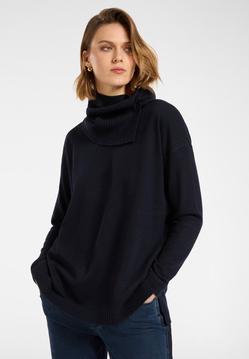 Maglione blu navy con collo a imbuto realizzato in tessuto morbido, con collo e polsini a coste e vestibilità comoda con spacchi laterali per facilitare i movimenti.