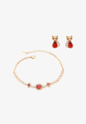 Gouden armband met rode en heldere stenen en bijpassende gouden oorbellen in de vorm van een vos, met rode druppelvormige stenen en heldere accenten.